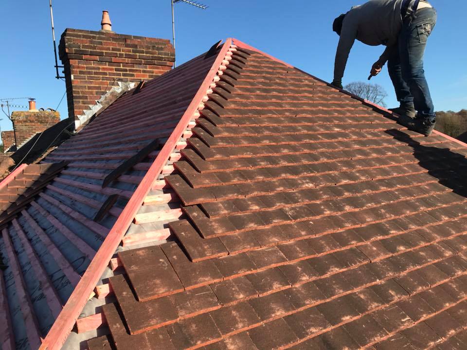 Roofer fixing new ridge tiles on a clay roof