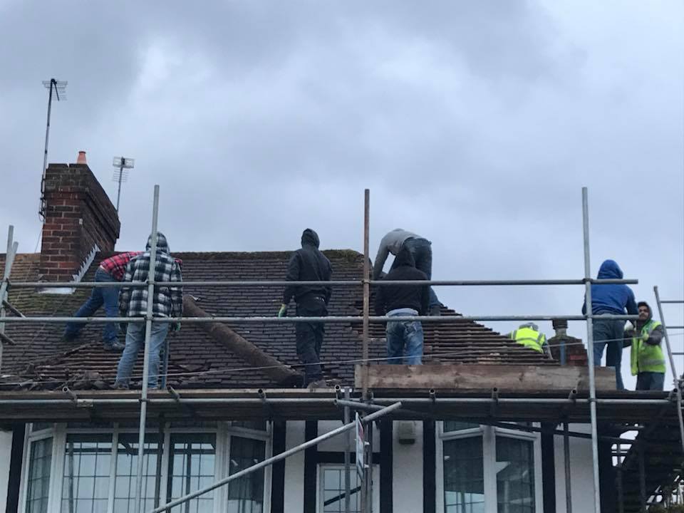 Roofing team stripping a roof from scaffolding